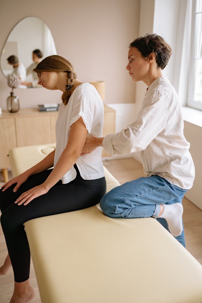 Chiropractor giving a spinal adjustment to a female patient in a clinic setting, focusing on back health.