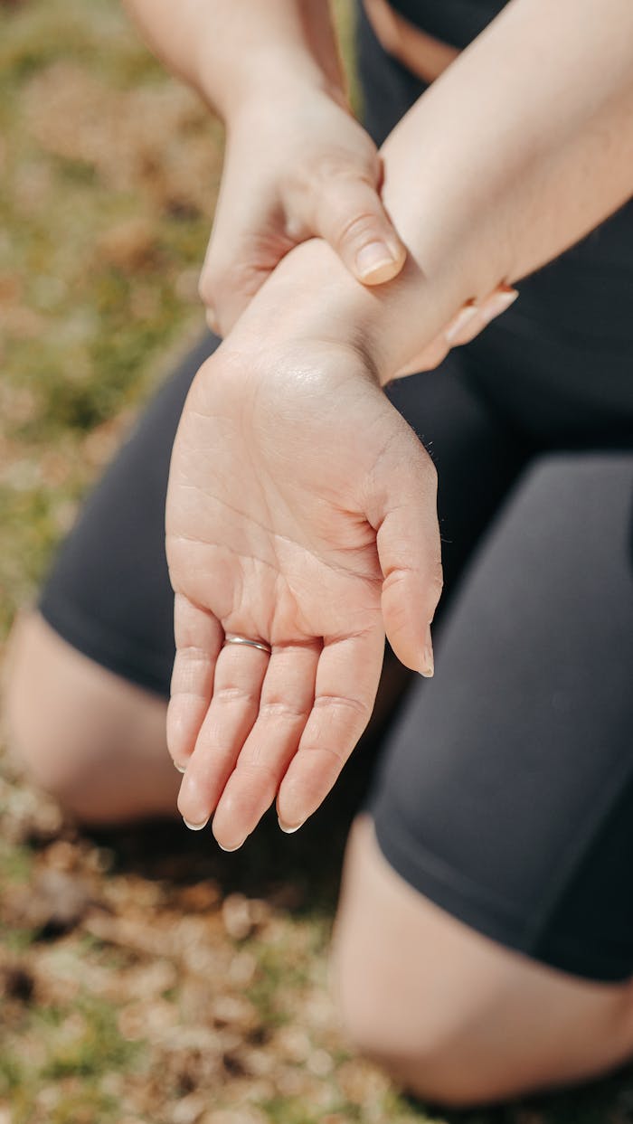 Close-up of a womans hand holding her wrist outdoors, symbolizing injury or pain relief.